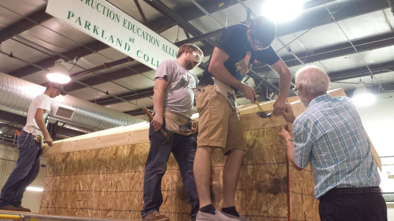 three students and instructor hammering on wooden structure